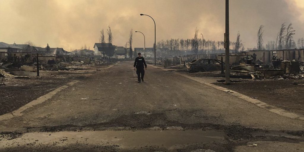 A Mounty examines fire damage in Fort McMurray (photo: RCMP)
