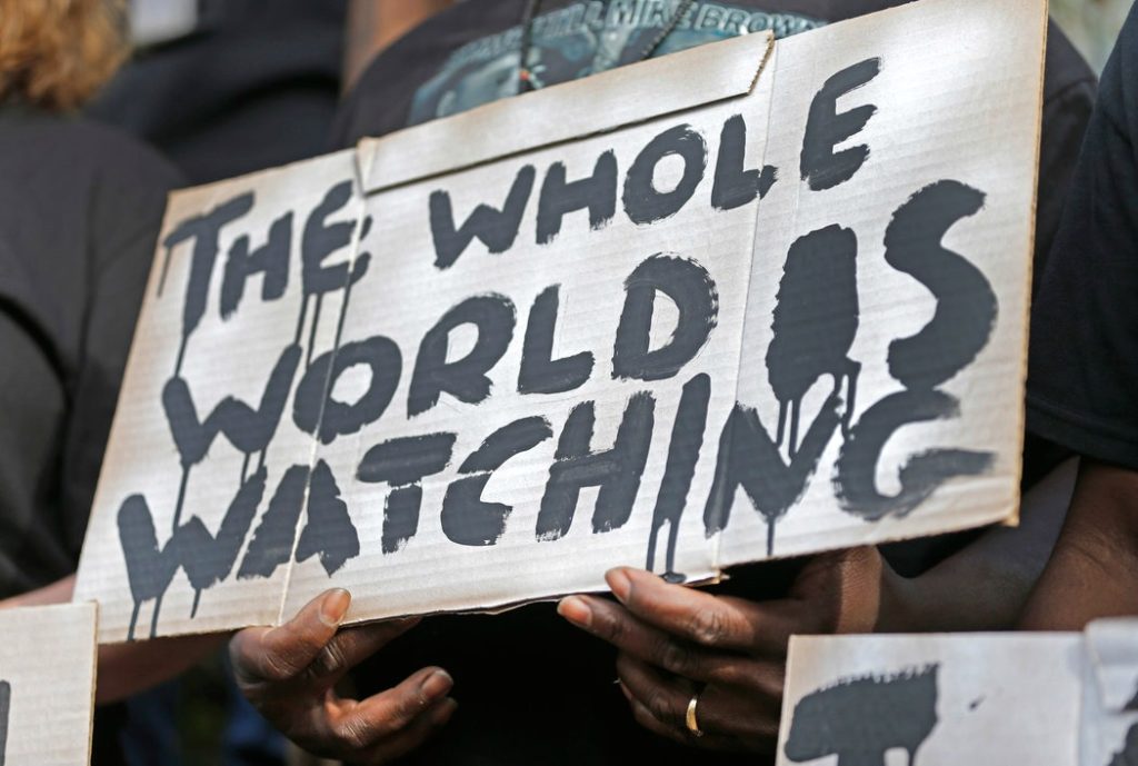 New York Times: The Whole World Is Watching (photo: Credit Chuck Burton/AP)