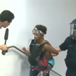 A CNN reporter attempts to interview a protester being taken away by police.