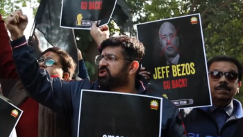 Workers protesting their treatment by Amazon, with a sign reading "Jeff Bezos Go Back."