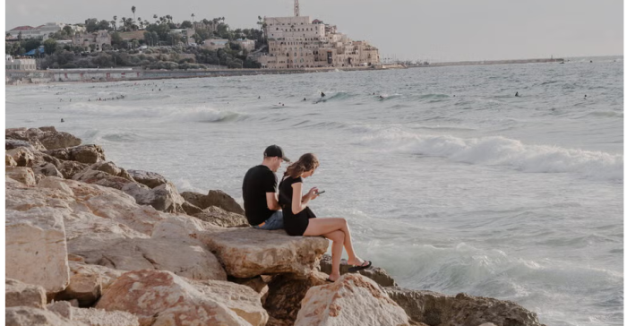 Imagen del New York Times que muestra a israelíes mirando sus teléfonos móviles en la costa mediterránea. Foto: Ofir Berman